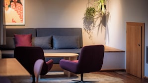 A modern living room with a sofa, two armchairs, a wooden coffee table, and a hanging plant. - Room Josefine - Comfort room with mountain view, Julius Appartements Wagrain (Hofmark)