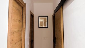 Ein schmaler Korridor mit Holztüren an beiden Seiten und einem gerahmten Bild an der Wand.