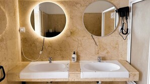 Ein Badezimmer mit zwei Waschbecken, zwei Spiegeln und einem an der Wand montierten Föhn.