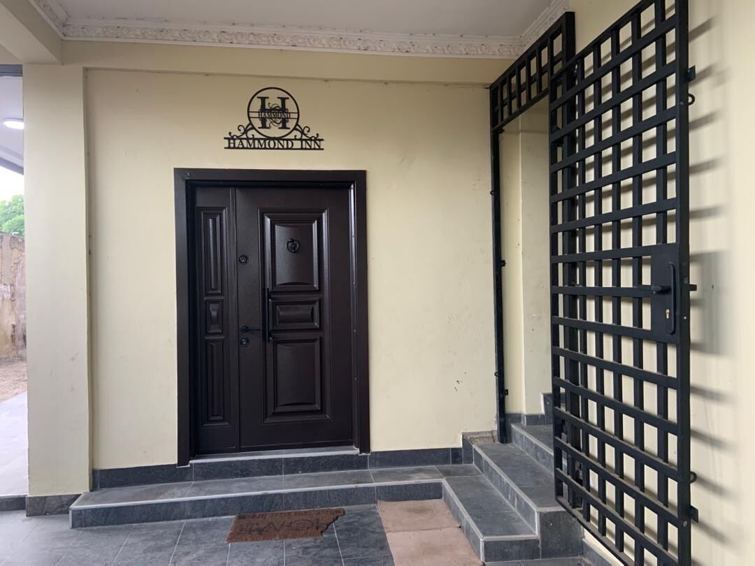 A black door with a sign above it, a gated entrance, and a small step leading to the door.