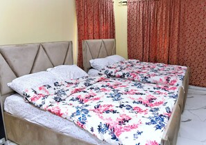 A double bed with floral bedding, a headboard, and a curtain. - Charming large 2-bedroom apartment with AC in vibrant Osu-Accra (Accra)