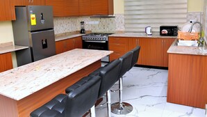 Eine moderne Küche mit Holzschränken, einem Edelstahlkühlschrank, einem Gasherd und einem eingebauten Backofen.