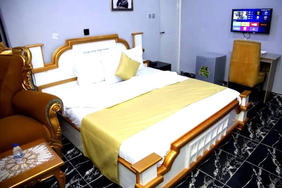 A hotel room with a bed, a chair, a small table, a television, and a picture on the wall.