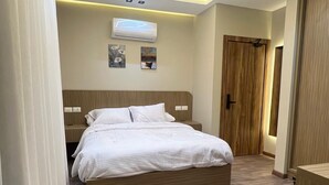 Ein Schlafzimmer mit einem Bett, Nachttischen, einem Holzschrank und einer Decken-Klimaanlage.