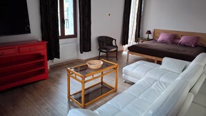 A room with a bed, a red dresser, a white sofa, a wooden table with a basket, and a television on the wall. - Furnished Appartment Au Pied du Mercantour (Fontan)