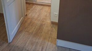 A room with a wooden floor, a white door, and a brown cabinet. - Furnished Appartment Au Pied du Mercantour (Fontan)