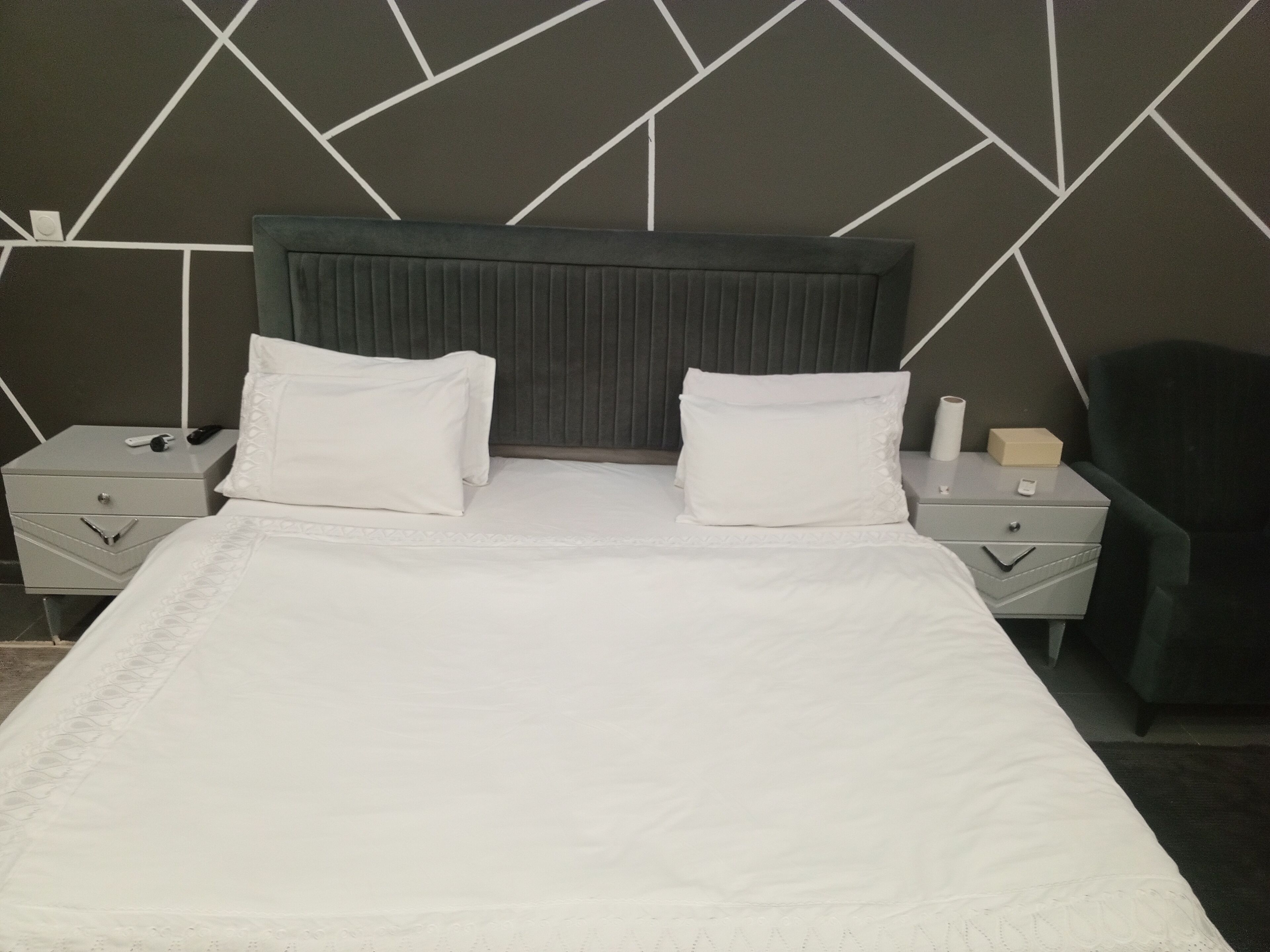 Camera d'albergo con un letto, due comodini, una testiera e una parete con motivo geometrico.