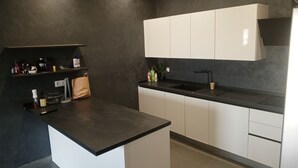 Eine moderne Küche mit dunklen Arbeitsplatten, weißen Schränken und einer schwarzen Spritzschutzwand.