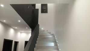 Eine moderne Treppe mit dunkler Handlauf und hellen Stufen, die zu einer Empfangsebene mit integrierter Beleuchtung führt.