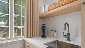 A modern kitchen with a stainless steel sink, a coffee maker, and a bottle of hand soap. - Bella Notte by the beach Studio 1 (Pleasure Point)