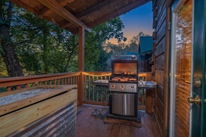 A wooden deck with a barbecue grill, a bench, and a view of the forest. - Sleeps 15, Dog Friendly Log Cabin, Hot Tub, Arcade, 4 Mi to Downtown Gatlinburg (Gatlinburg)