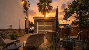 A patio with wicker furniture, a small table, and a garage door. - Bella Notte by the beach Studio 2 (Pleasure Point)