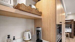 A modern kitchen with a coffee maker, kettle, and dish soap on the counter. - Bella Notte by the beach Studio 2 (Pleasure Point)