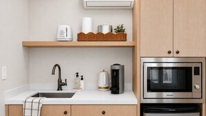 A modern kitchen with a sink, faucet, coffee maker, microwave, and a refrigerator. - Bella Notte by the beach Studio 2 (Pleasure Point)