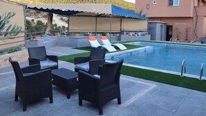 An outdoor pool area with lounge chairs and a covered seating area.