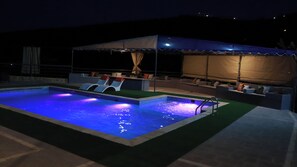Ein Swimmingpool mit Sonnensegel und Liegestühlen.