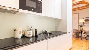 Eine moderne Küche mit Mikrowelle, Wasserkocher, Toaster und Spüle.
