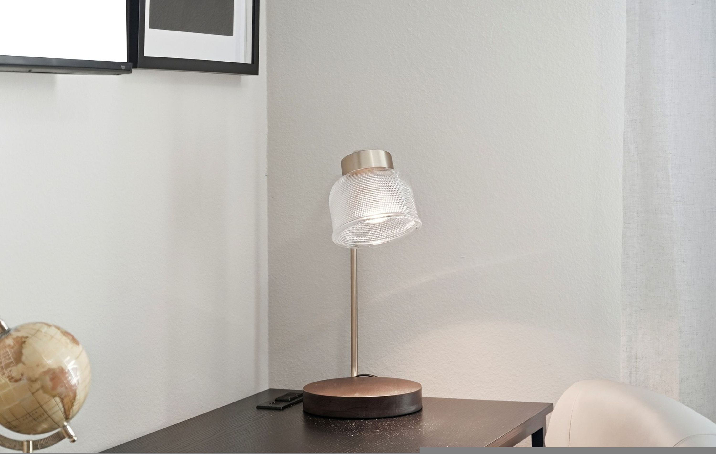En moderne lampe med en cylinderformet skærm på et træbord.