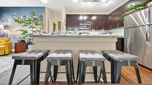 A modern kitchen with dark cabinets, stainless steel appliances, and a cityscape mural. - Stylish 2BR w Balcony Pool Pet-friendly 15 (Tampa)