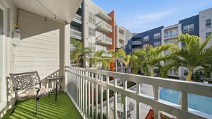 A balcony with a bench, a pool, and a view of multi-story buildings. - Stylish 2BR w Balcony Pool Pet-friendly 15 (Tampa)