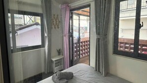 A bedroom with a bed, a window, a door, and a view of the outside. - Home Nha Gao Da Lat (Xuan Huong - Da Lat)