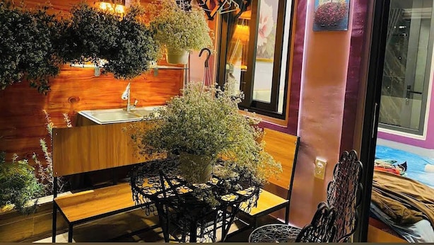 A room with a wooden wall, a sink, a table with chairs, and hanging plants. - Home Nha Gao Da Lat (Xuan Huong - Da Lat)