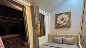 A bedroom with a bed, a window with curtains, a painting on the wall, and a balcony with a railing. - Home Nha Gao Da Lat (Xuan Huong - Da Lat)