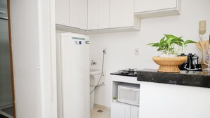 Een kleine keuken met een koelkast, magnetron en een klein spoelbakje.
