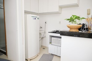 A compact kitchen with a refrigerator, microwave, and a small sink. - Cozy apartment 702/703 North, 3 min from Mané Garrincha Stadium, 5 min from Ulysses Guimarães Stadium. (Brasília)