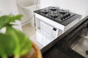 A kitchen with a gas stove, a microwave, and a sink. - Cozy apartment 702/703 North, 3 min from Mané Garrincha Stadium, 5 min from Ulysses Guimarães Stadium. (Brasília)