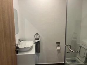Ein Badezimmer mit Waschbecken, Handtuchhalterung, Toilettenpapierhalter und Duschbereich.