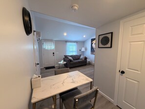 A modern living room with a sofa, a dining table, and a door.
