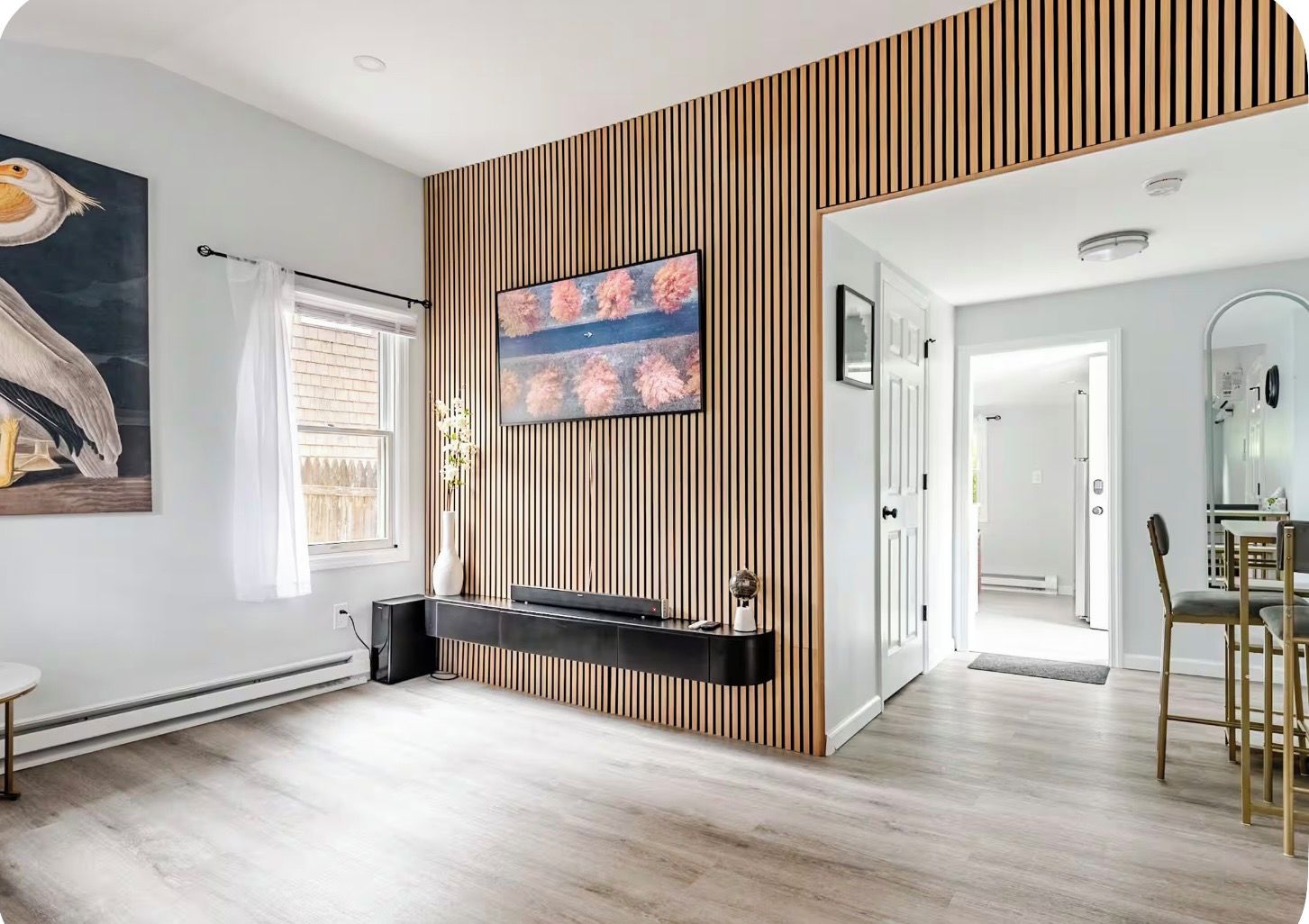 Una sala de estar moderna con una pared de acento de madera, un televisor de pantalla plana, una chimenea y un comedor con una silla y una mesa.