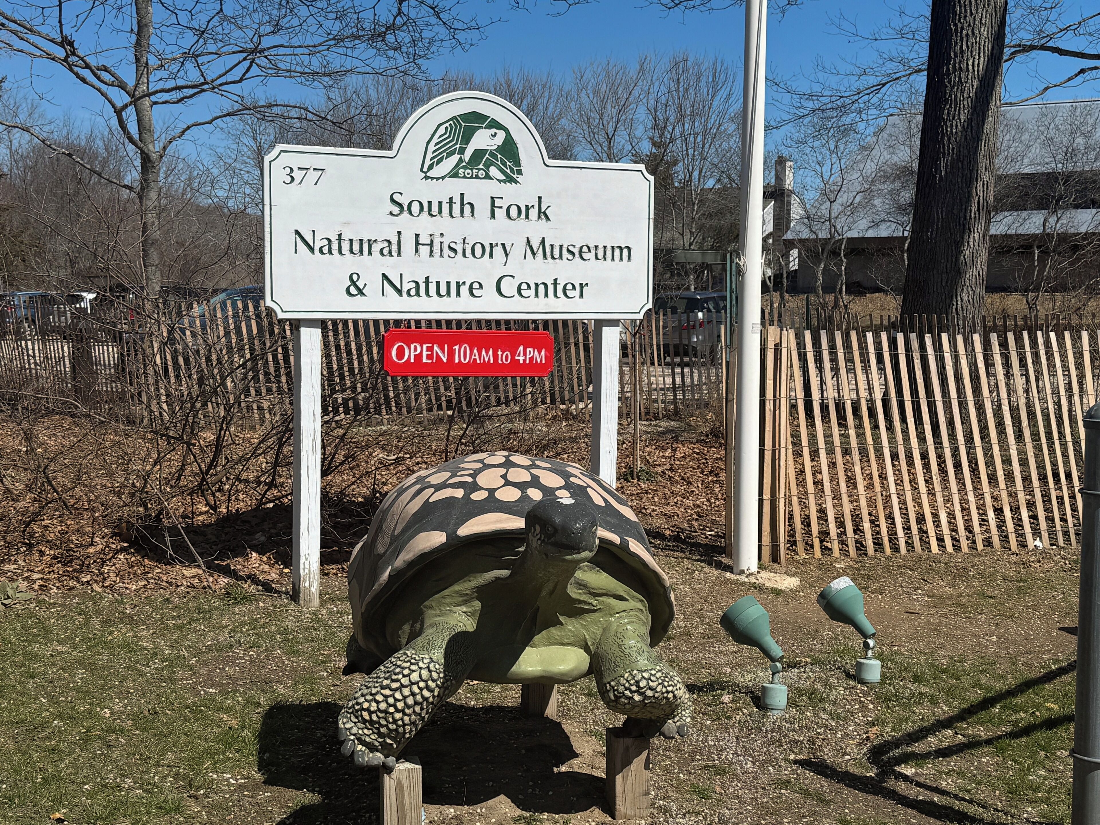 A sign for the South Fork Natural History Museum & Nature Center with a tortoise sculpture.