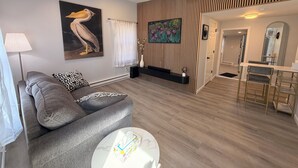 A modern living room with a grey sofa, a round coffee table, and a painting of a pelican.
