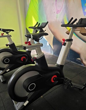 Bicicletas estáticas de gimnasio con un gran mural en la pared.