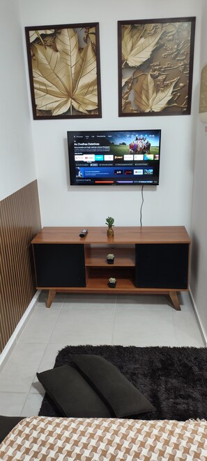 Ein modernes Wohnzimmer mit einem an der Wand befestigten Flachbildfernseher, einer Holzunterhaltungsecke darunter und einem schwarzen, flauschigen Teppich auf dem Boden.