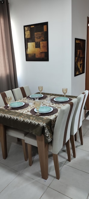 A dining table set with plates, glasses, and placemats, surrounded by chairs with striped cushions. - Cabo Branco Beach. Two-Bedroom Apartment. Up to 7 people. (João Pessoa)