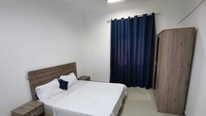 A bedroom with a bed, nightstands, a wardrobe, and a curtain.