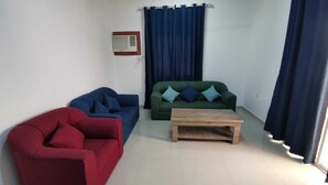 A living room with a red sofa, a green sofa, and a wooden coffee table.