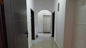 A corridor with a tiled floor, white walls, and doors on both sides.