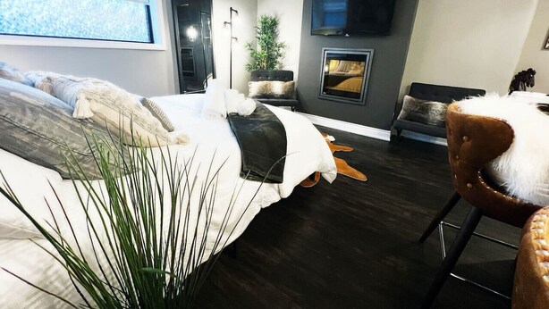 Une chambre moderne avec un grand lit, un téléviseur fixé au mur et une cheminée.