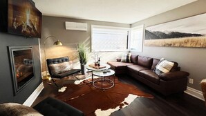 A modern living room with a brown leather sofa, a round coffee table, and a large brown and white rug. - Dreamy Escape | Cozy & Stylish Stay for Two (London)