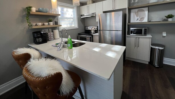 A modern kitchen with a central island, stainless steel appliances, and pendant lighting. - Dreamy Escape | Cozy & Stylish Stay for Two (London)