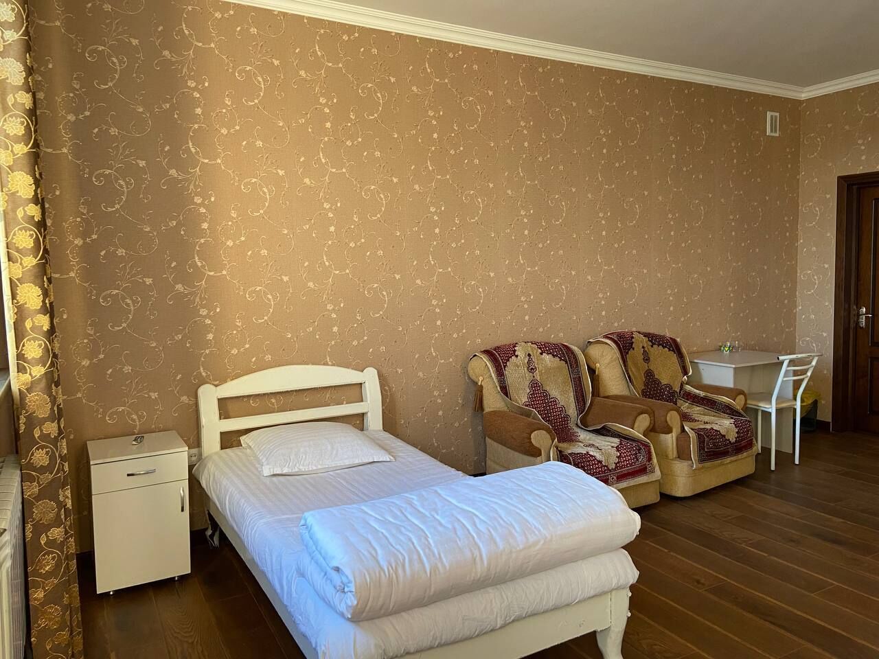 Una camera da letto con un letto, una sedia, una scrivania e un comodino.