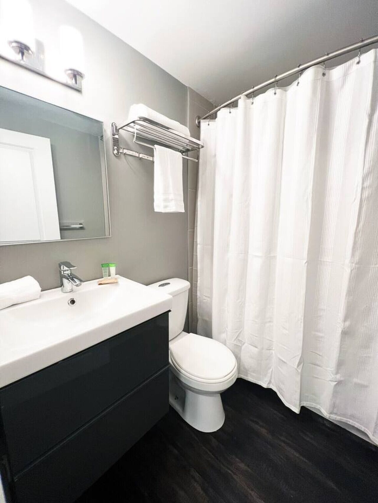 A modern bathroom with a white sink, mirror, and toilet.