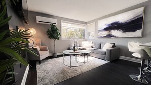 En moderne stue med en grå sofa, et rundt sofabord og et stort abstrakt billede på væggen.