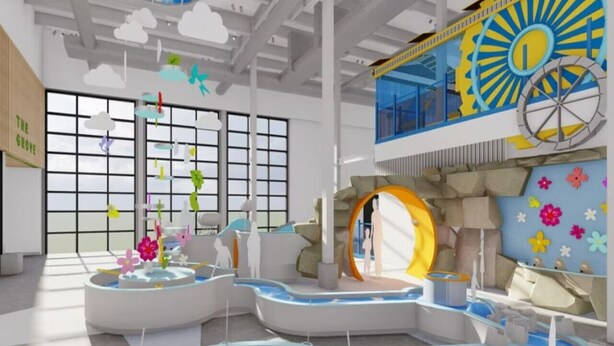 A modern indoor space with large windows, a central water feature, and a distinctive sun wheel decoration.