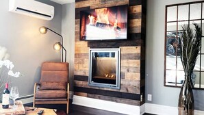 A living room with a fireplace, a mounted TV, and a comfortable seating area.