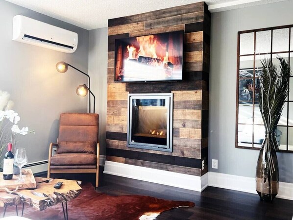 A living room with a fireplace, a mounted TV, and a comfortable seating area.